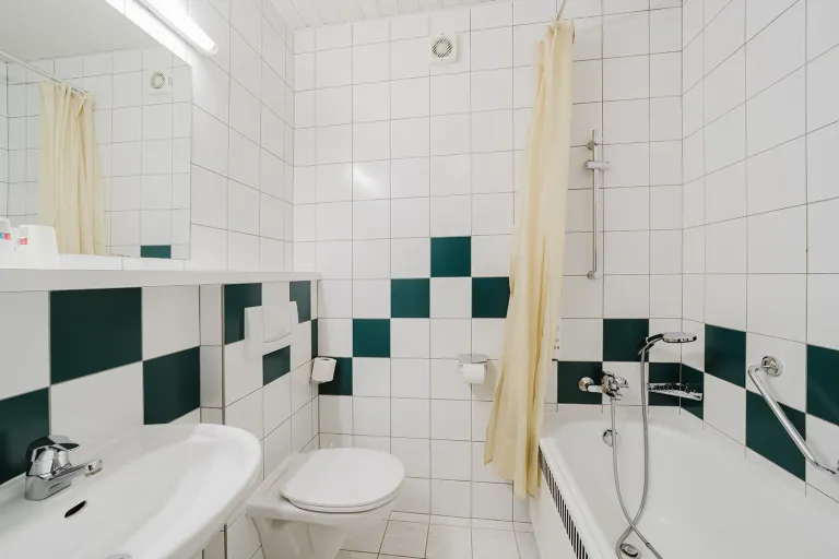 Bad mit Badewanne und grün-weißen Fliesen im Doppelzimmer mit privater Garage im Motel Baden
