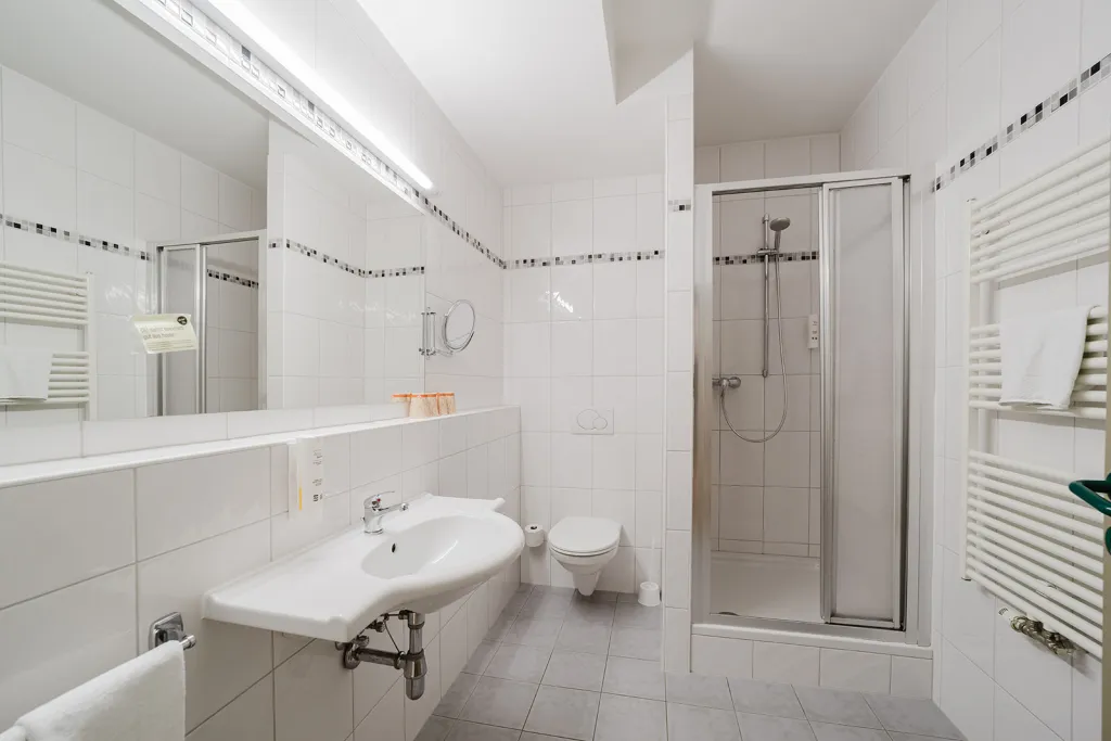 Badezimmer mit Duschkabine, Waschtisch und Handtuchheizkörper im Motel Baden
