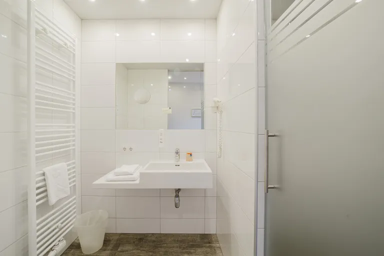 Badezimmer mit Glastür, Waschtisch und Handtuchheizkörper im Motel Baden
