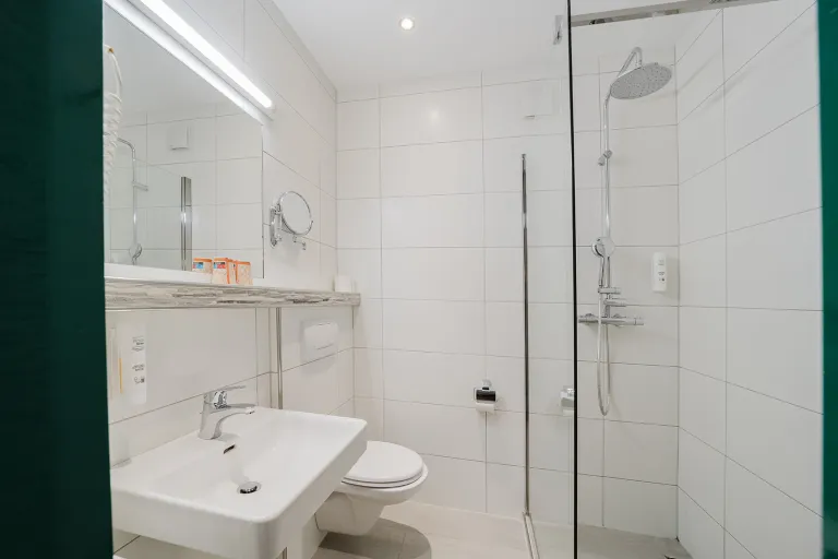 Modernes Badezimmer mit bodengleicher Dusche, Waschtisch und WC im Motel Baden