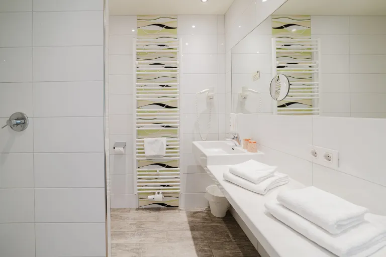 Badezimmer mit Waschtisch, Handtüchern und Mosaikfliesen im Motel Baden