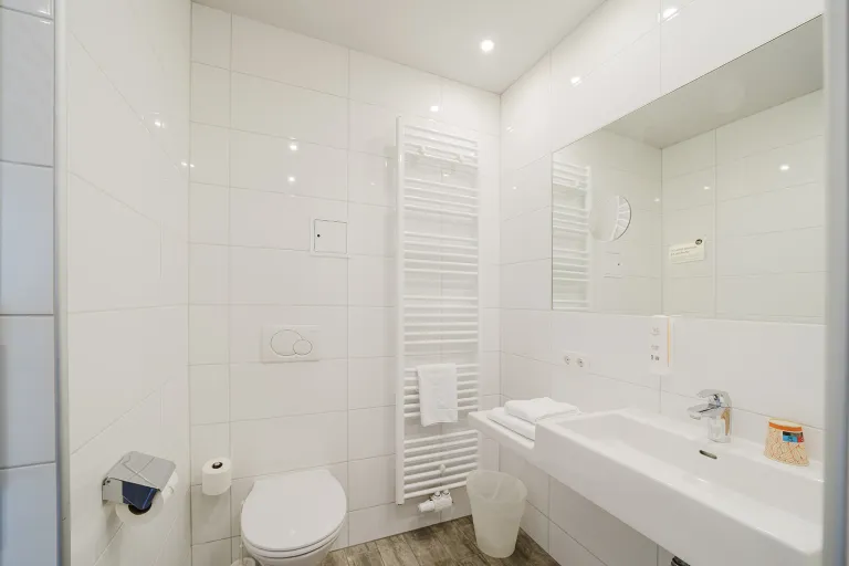Badezimmer mit Waschtisch, Spiegel und WC im Motel Baden