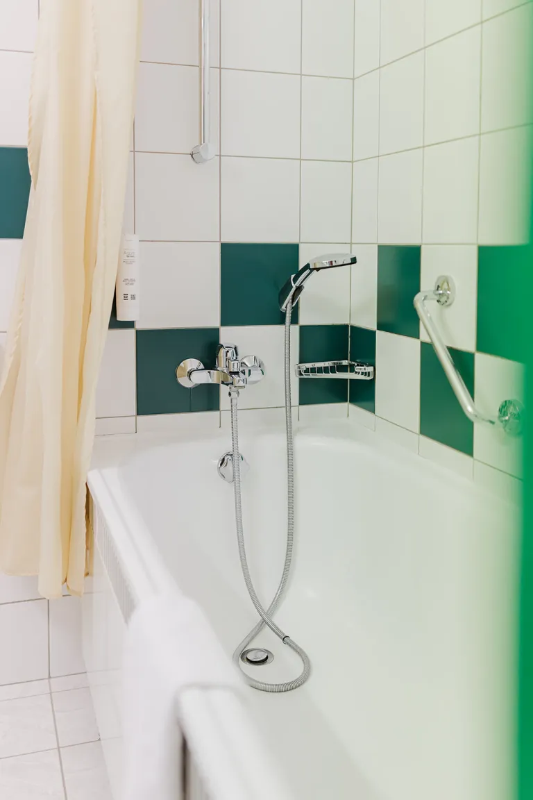 Badewanne im grün-weiß gefliesten Bad im Motel Baden