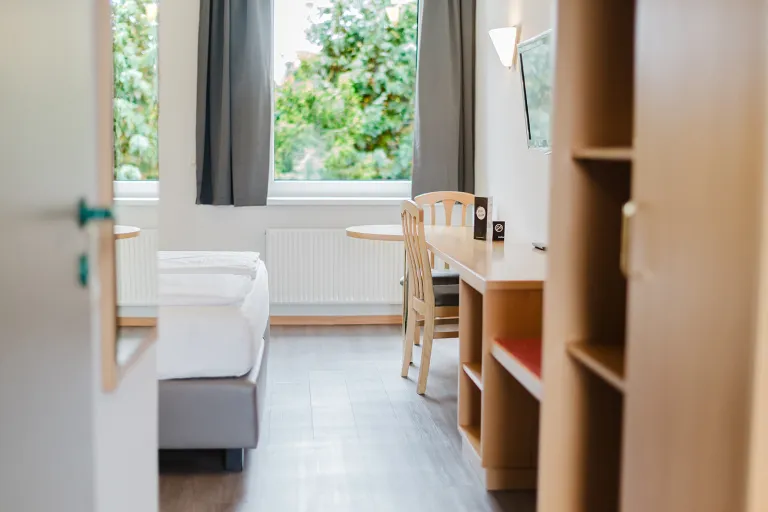 Doppelzimmer mit Bett, Regal und Blick ins Grüne im Motel Baden
