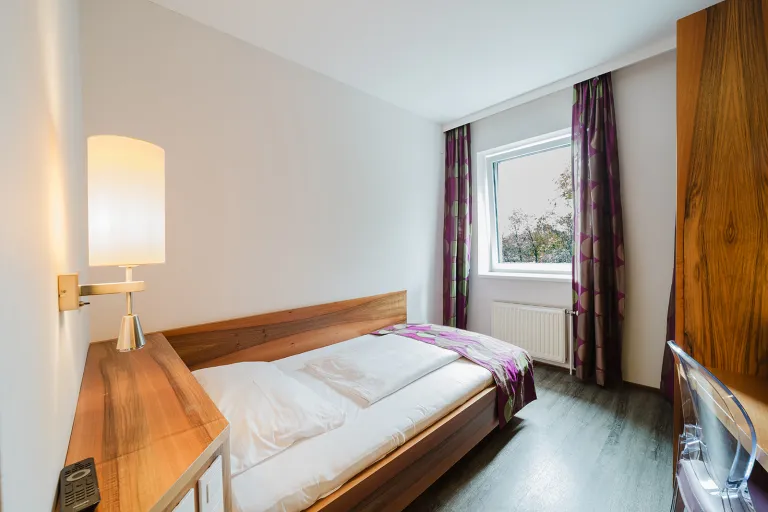 Bett mit Leselampe am Fenster im Motel Baden