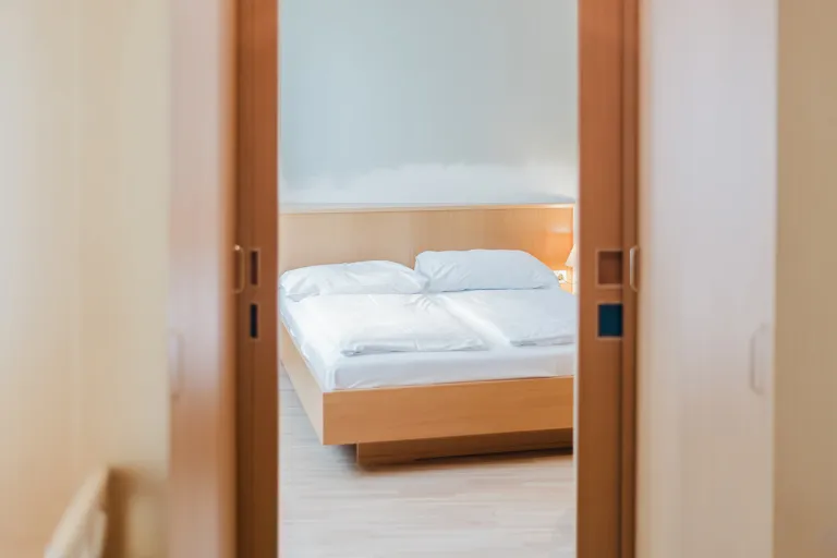 Blick durch die Zimmertür auf das Bett im Motel Baden