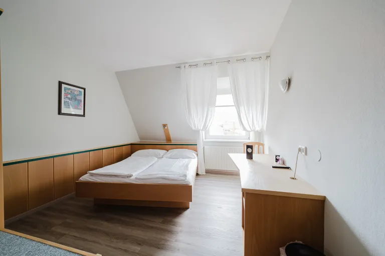 Doppelzimmer im Dachgeschoss mit Doppelbett und Schreibtisch im Motel Baden