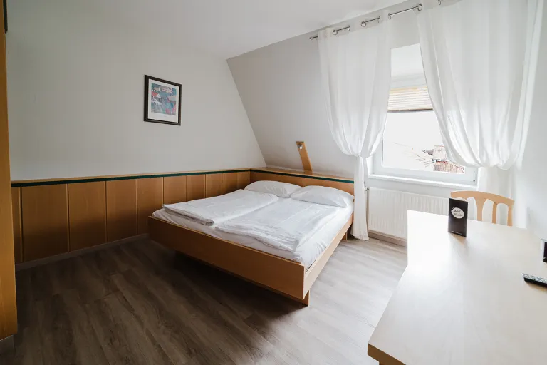 Doppelbett unter der Dachschräge am Fenster im Motel Baden
