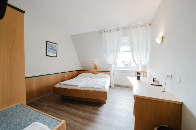 Doppelzimmer im Dachgeschoss mit Doppelbett und Schreibtisch im Motel Baden