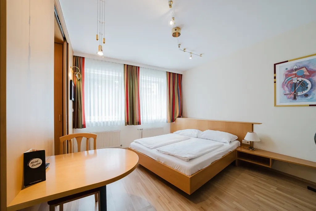 Helles Zimmer mit Doppelbett, Holzmöbeln und Tisch Helles Zimmer mit Doppelbett, Holzmöbeln und Tisch im Motel Baden