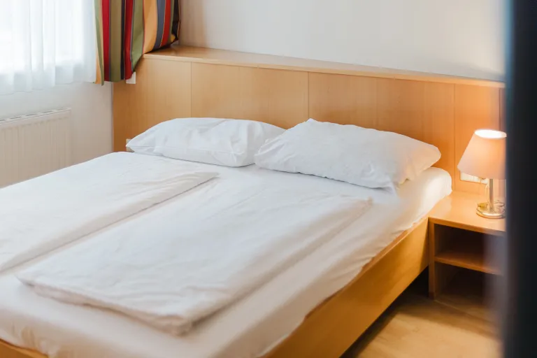 Doppelbett mit Nachttischlampe im Motel Baden
