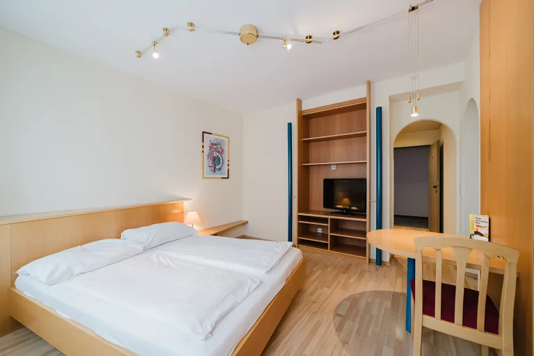 Zimmer mit Doppelbett, Schreibtisch und Schrankwand mit TV im Motel Baden