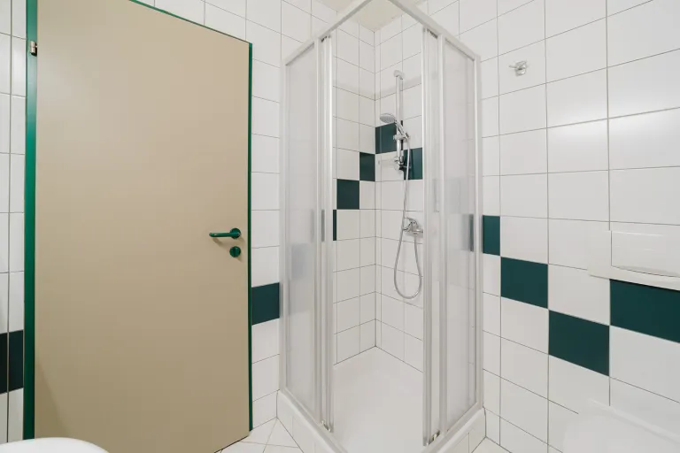 Duschkabine im grün-weiß gefliesten Bad im Motel Baden