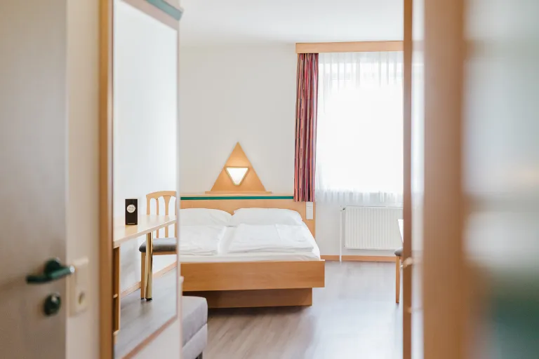 Blick durch die Tür auf das Doppelbett im Doppelzimmer mit privater Garage im Motel Baden