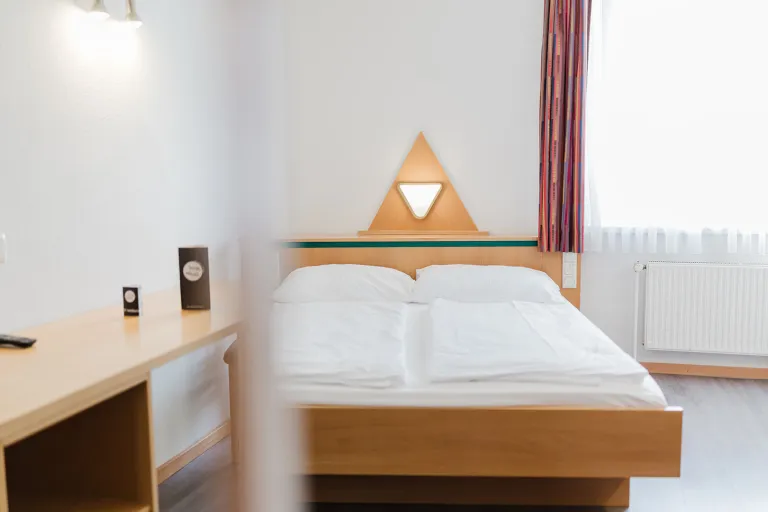 Doppelbett und Schreibtisch im Doppelzimmer mit privater Garage im Motel Baden