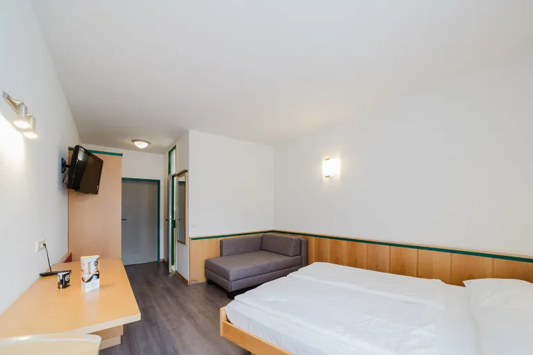 Doppelzimmer mit privater Garage: Bett, Sofa und Flat-TV im Motel Baden