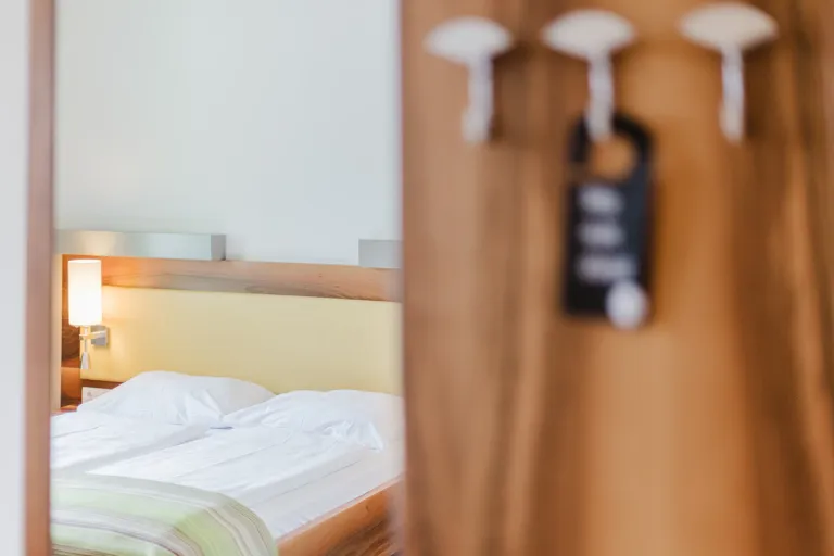 Garderobe mit Türhänger und Bett im Motel Baden