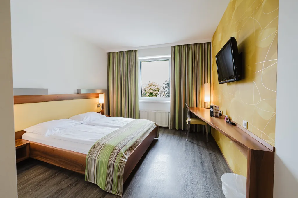 Doppelbett vor gelber Akzentwand mit Flat-TV Doppelbett vor gelber Akzentwand mit Flat-TV im Motel Baden