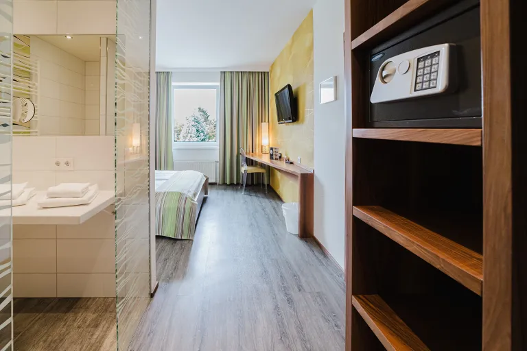 Doppelzimmer mit Regal, Safe und offenem Badbereich im Motel Baden