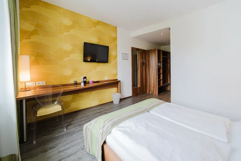 Doppelzimmer mit gelber Akzentwand, Flat-TV, Schreibtisch und Doppelbett im Motel Baden