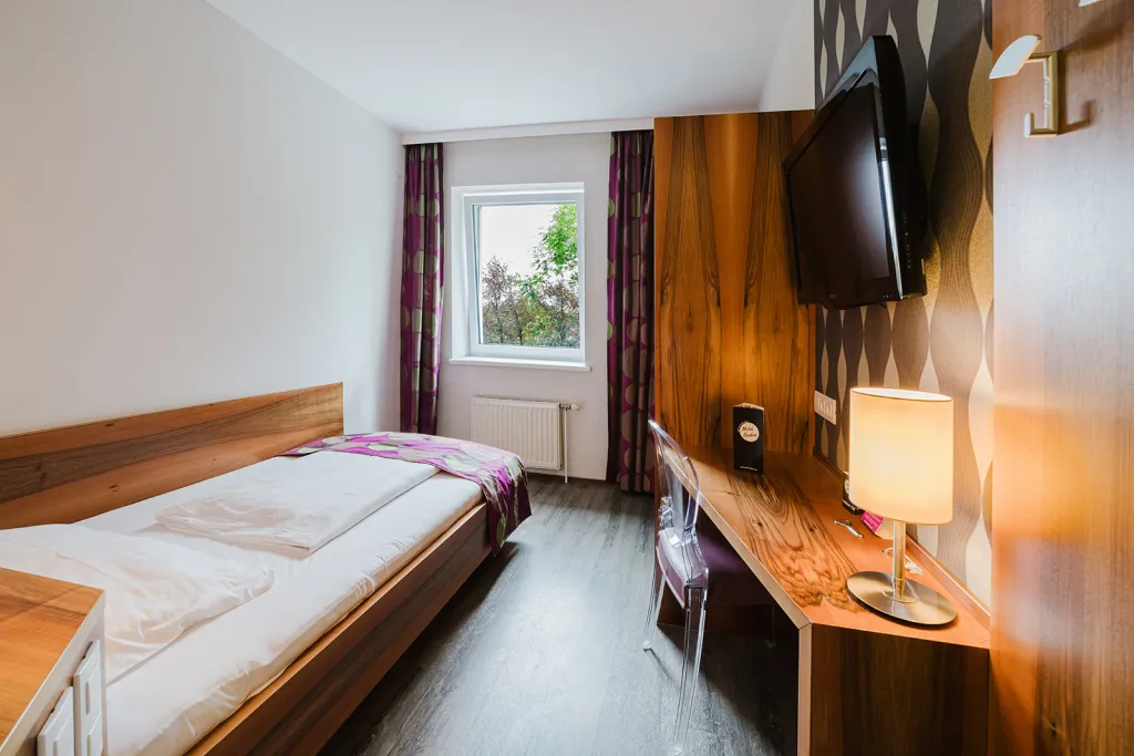 Zimmer mit Bett, Holzwand mit Flat-TV und Schreibtisch Einzelzimmer mit Bett, Holzwand mit Flat-TV und Schreibtisch im Motel Baden