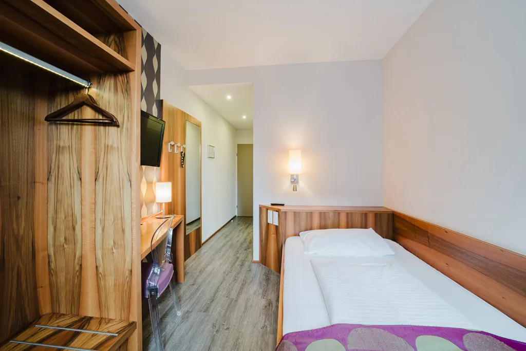 Einzelzimmer mit Bett und Holzgarderobe im Motel Baden