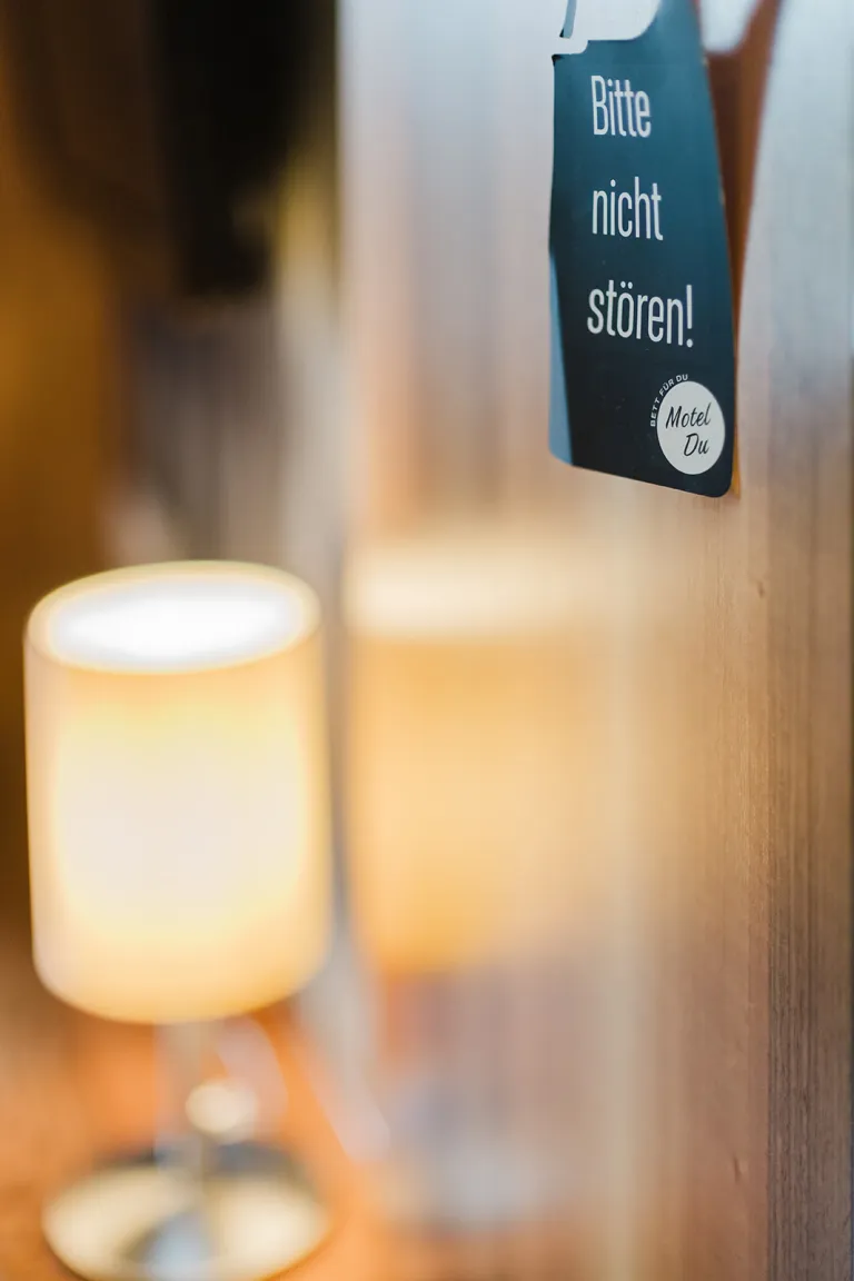 Lampe und Türhänger im Zimmer des Motel Baden