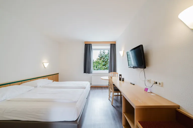 Modernes Doppelzimmer mit Doppelbett, Flat-TV und Schreibtisch im Motel Baden