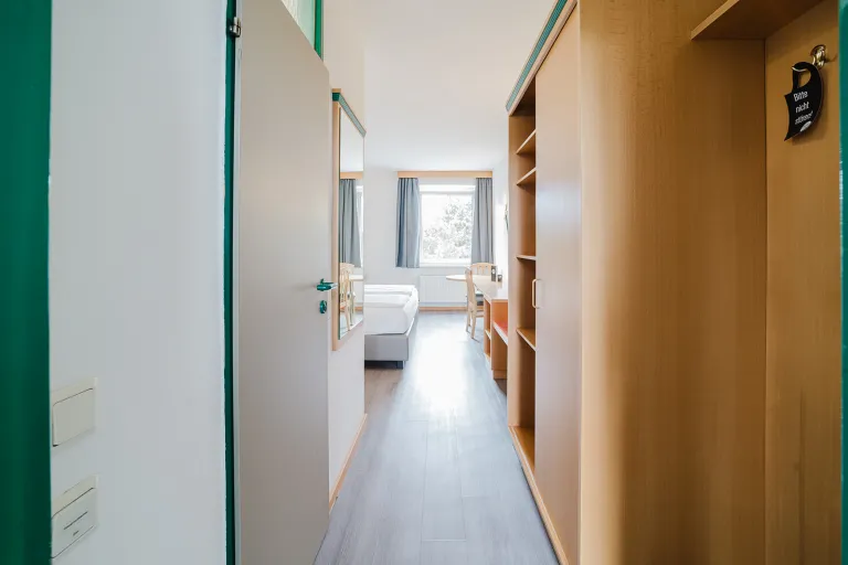 Modernes Doppelzimmer mit Garderobe und Blick zum Fenster im Motel Baden