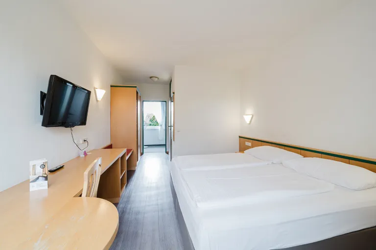 Modernes Doppelzimmer mit Wand-TV, Schreibtisch und Doppelbett im Motel Baden