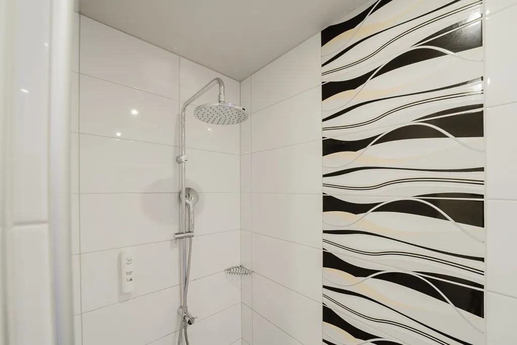 Regendusche mit schwarz-weißen Wellenfliesen im Motel Baden