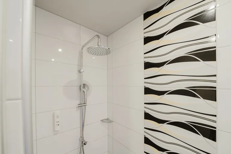 Regendusche mit schwarz-weißen Wellenfliesen im Motel Baden