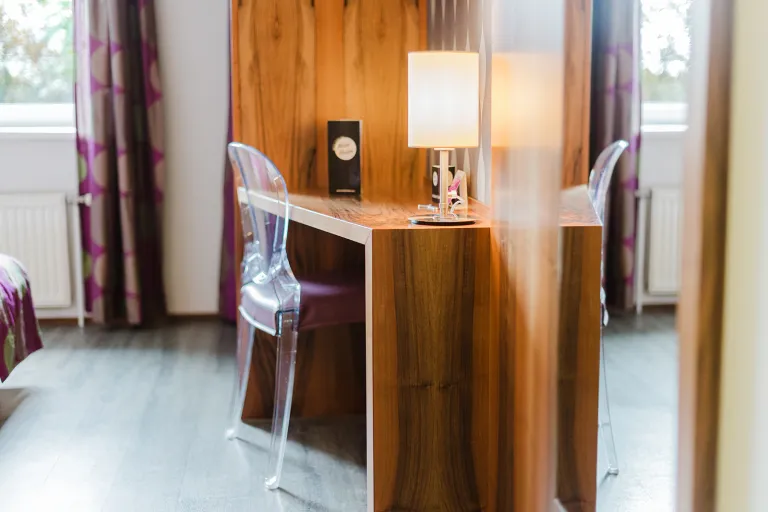 Schreibtisch mit Lampe und transparentem Stuhl im Motel Baden