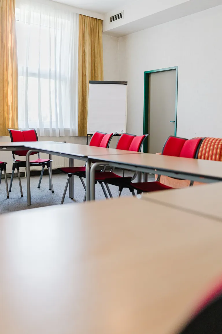 Großer Seminarraum mit Tischen und Flipchart im Motel Baden