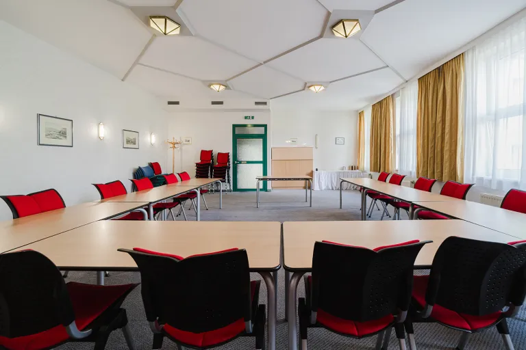Großer Seminarraum im 1. Stock mit Tischen in U-Form und Tageslicht im Motel Baden
