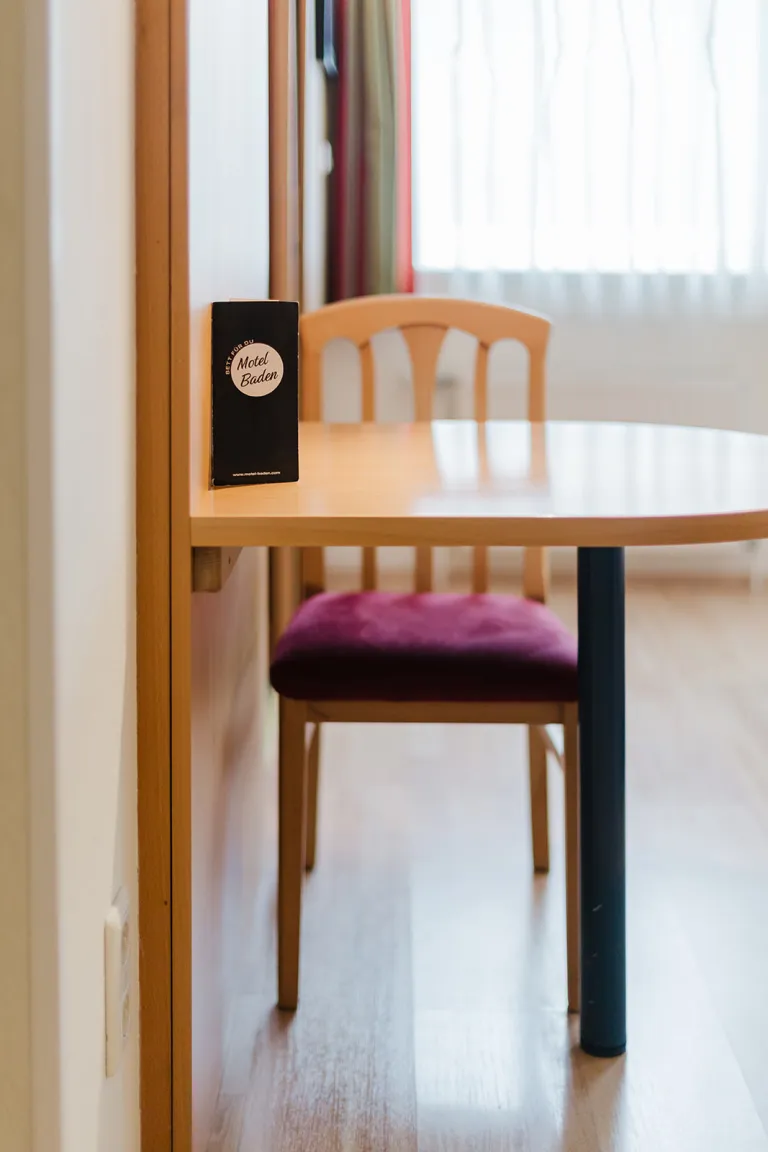 Tisch mit Stuhl und Info-Flyer im Zimmer des Motel Baden