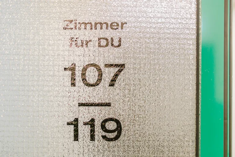 Wegweiser „Zimmer für DU 107–119“ im Motel Baden