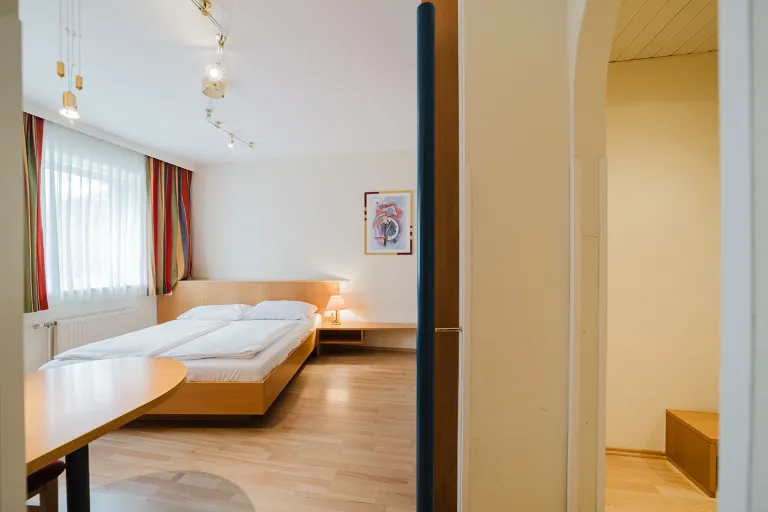 Blick durch die Verbindungstür in das Zimmer mit Doppelbett im Motel Baden