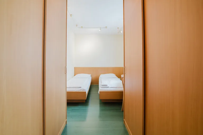 Blick durch die Holztür in ein Zimmer mit zwei Einzelbetten im Motel Baden