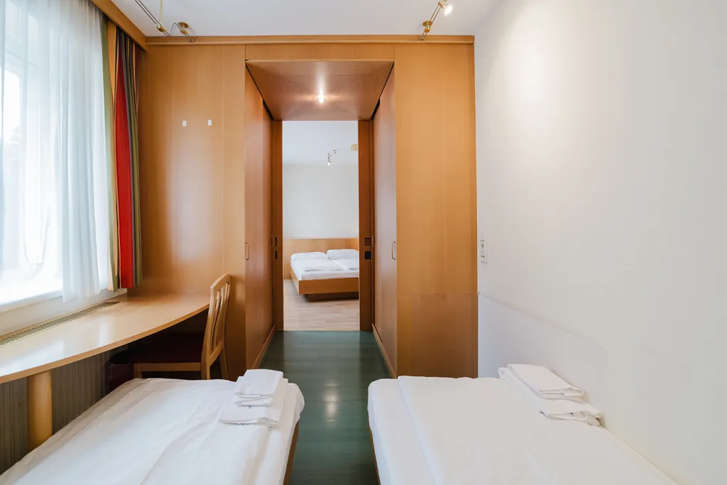Zwei Einzelbetten, Schreibtisch und Durchgang im Motel Baden